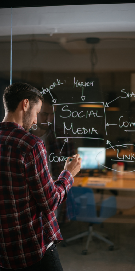 Mann schreibt an eine Glaswand mit Ideen zum Thema soziale Medien.